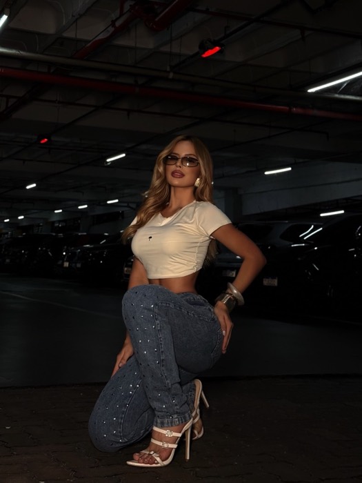 Manu Carneiro em locação externa, top branco e jeans
